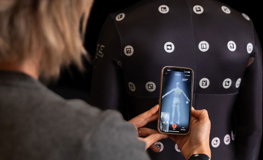 L'immagine rappresenta un uomo che indossa la tuta Proke mentre con l'app vengo prese le misure corporee con la tecnologia innovativa Proke