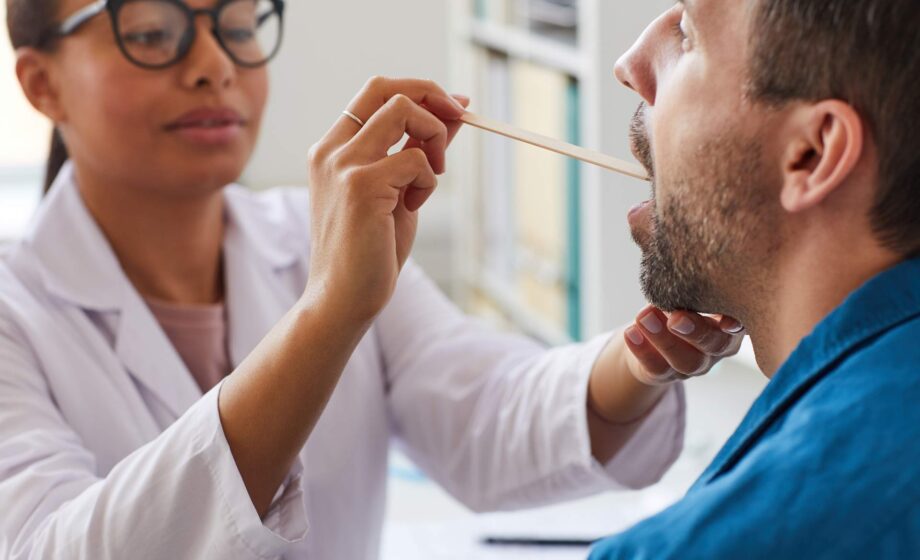 Una dottoressa mentre esamina la bocca di un paziente alla ricerca di segni di tumore orofaringei da HPV