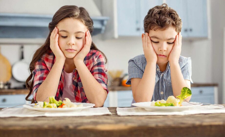 Due bambini che guardano con tristezza il piatto di verdure. In Italia arriva un vademecum per favorire un’alimentazione sana ed equilibrata sin da piccoli.
